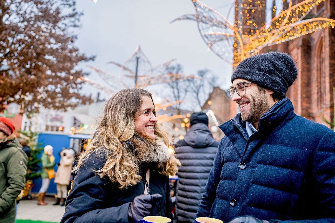 Paar trinkt aus Glühweintassen vor dem Hintergrund der Marktkirche