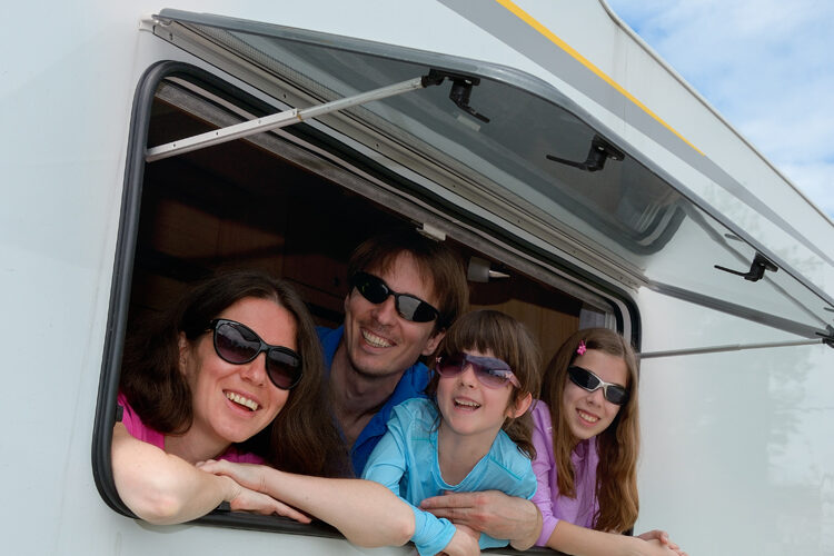 Vierköpfige Familie schaut aus dem Fenster des Campingwagens
