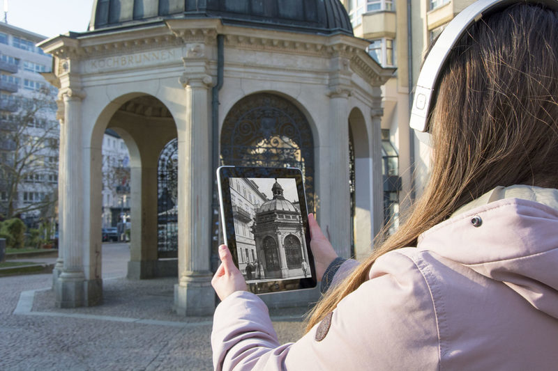 Eine Frau mit einem Tablet vor der Sehenswürdigkeit