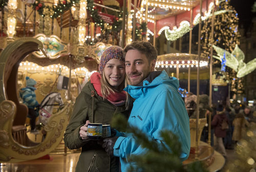 Weihnachtlichen Kurzrundgänge Sternschnuppenmarkt: Junges Paar am Karussell mit Glühwein.