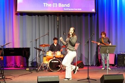 Frau mit Mikrofon auf Bühne mit Band