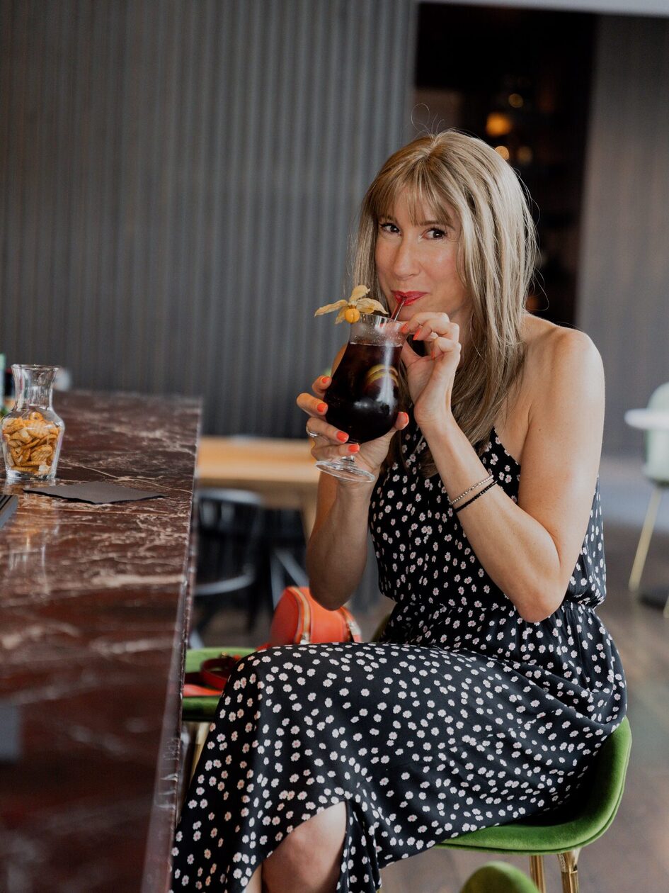 Junge Frau mit blauem Kleid auf rotem Sofa beim Speisen.