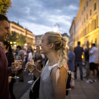 Frau und Mann mit Weinglas vor beleuchtetem Rathaus und Hessischem Landtag