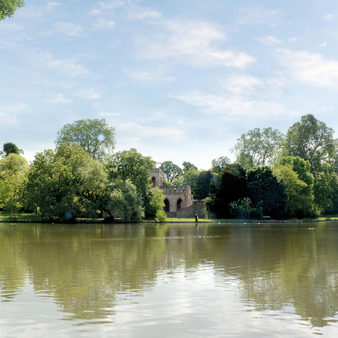 Weiher im Schlosspark mit Schlösschen und sichtbarer Kirchturmspitze