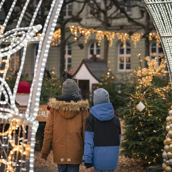 Zwei Kinder laufen durch einen Lichterbogen