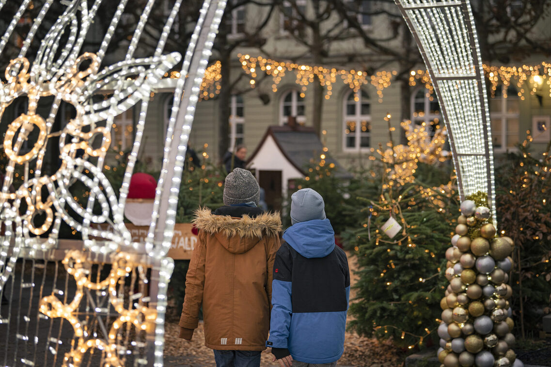 Zwei Kinder laufen durch einen Lichterbogen