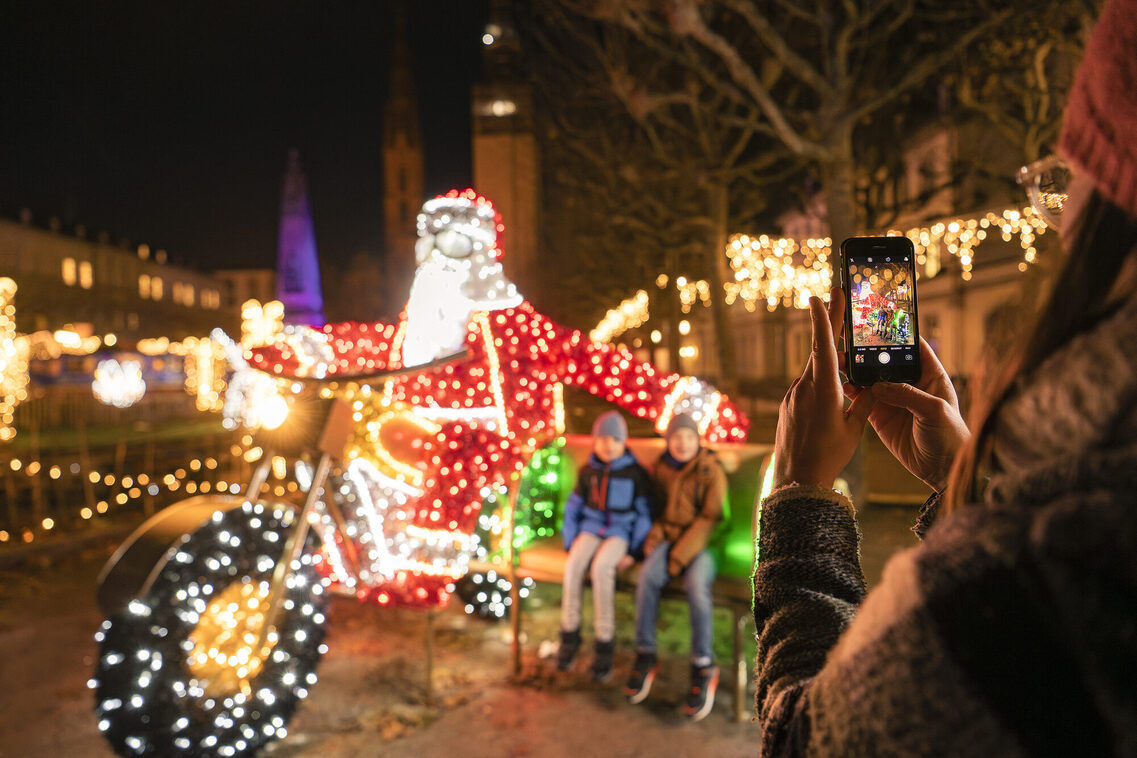 Kinder auf einer Bank neben einer Nikolausfigur auf einem Motorrad aus Lichtern