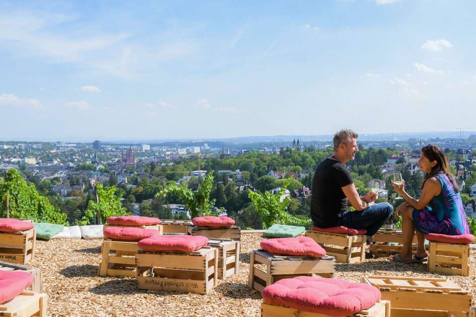 Un homme et une femme boivent du vin en admirant la vue sur la ville