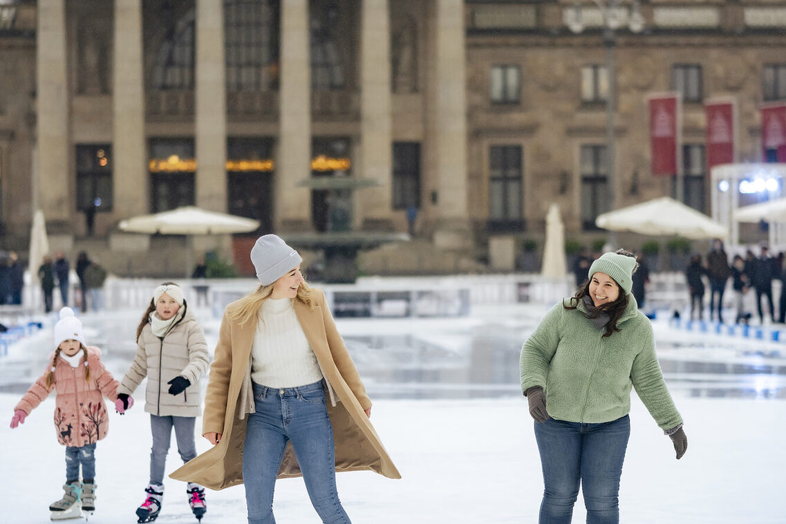 Zwei Frauen laufen Schlittschuh auf der Eisbahn vor dem Kurhaus.