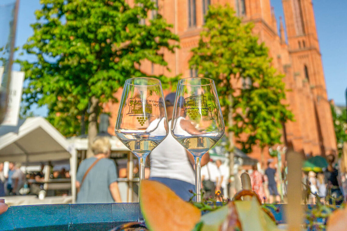 Due bicchieri di vino davanti a una chiesa di mercato sfocata