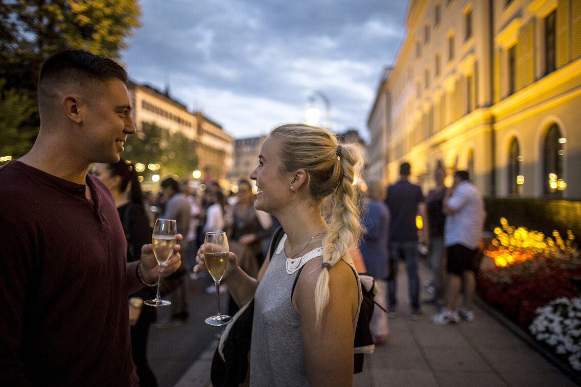 Donna e uomo con bicchiere di vino davanti al municipio illuminato e al parlamento dell'Assia