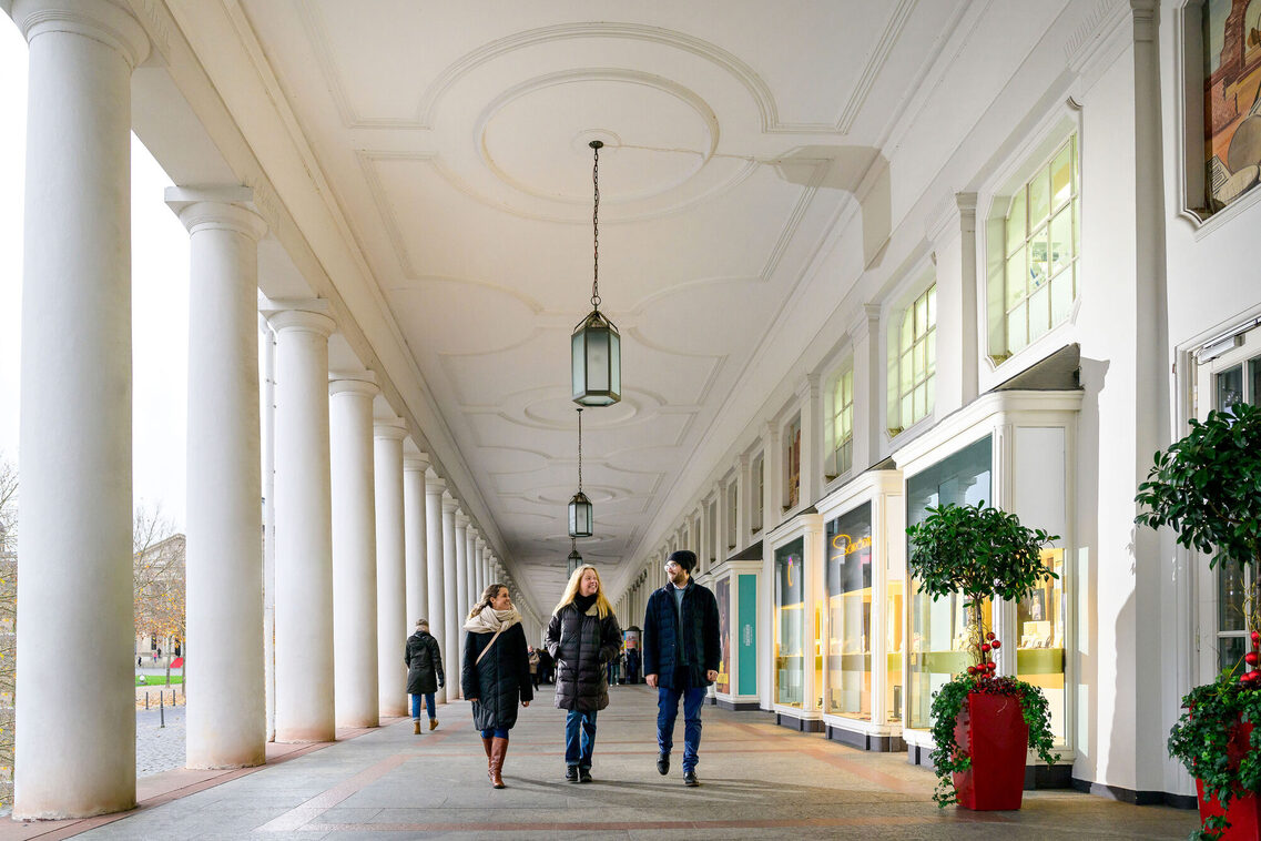 Drei junge Menschen laufen entlang der Kolonnaden