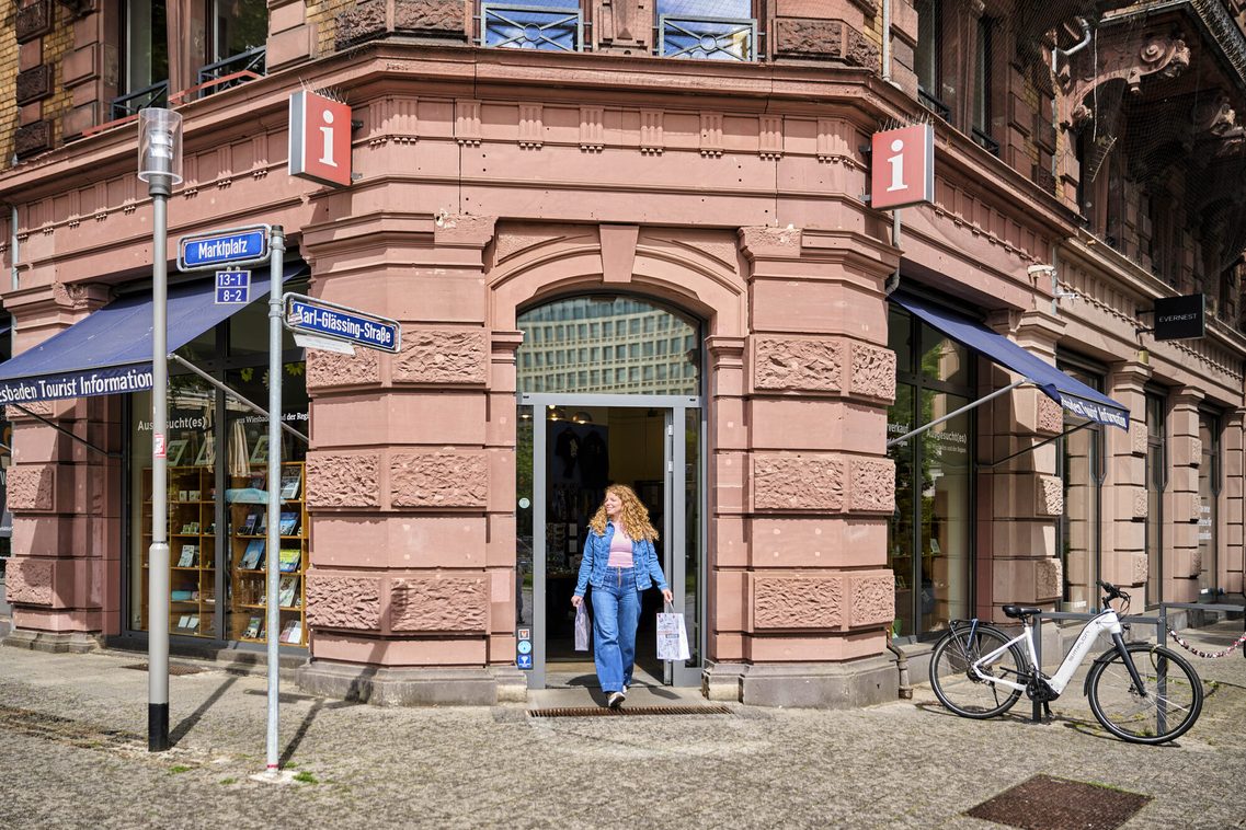 Frau kommt mit Tüte aus der Tourist Information am Marktplatz