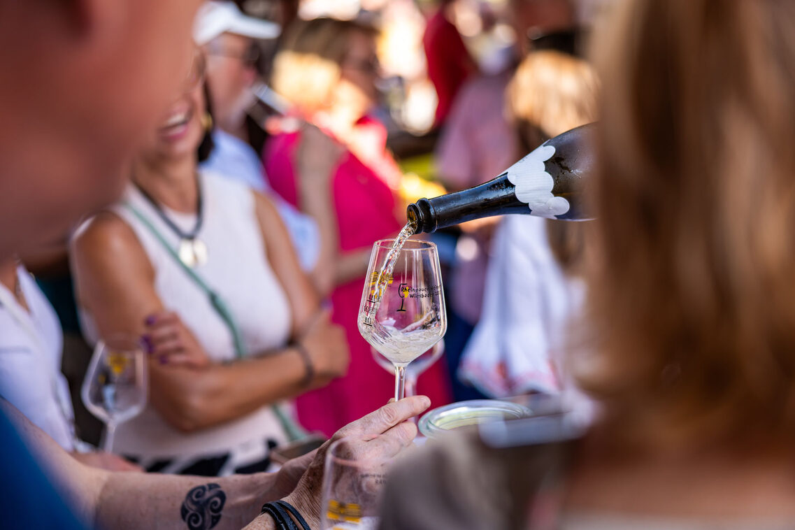 Eine Hand mit einem Wein schenkt Wein aus