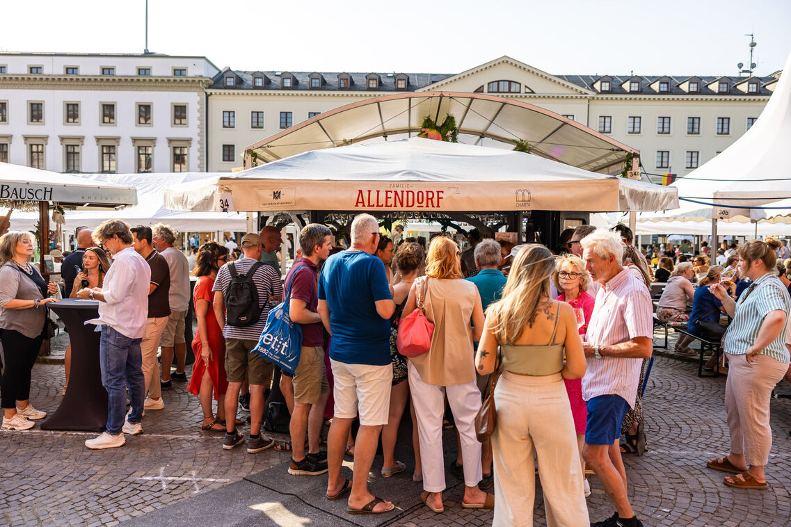 Frauen und Männer stehend am Weinstand