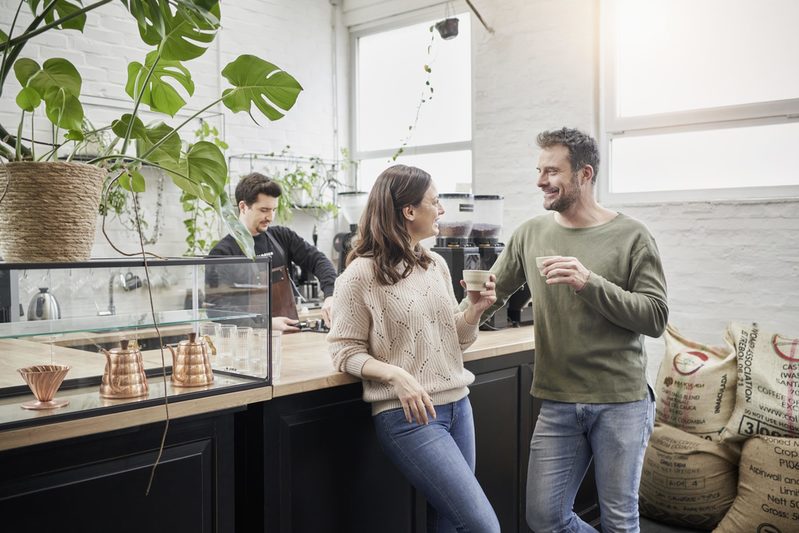 Ein Mann und eine Frau stehen und trinken Kaffee in einer Kafferösterei