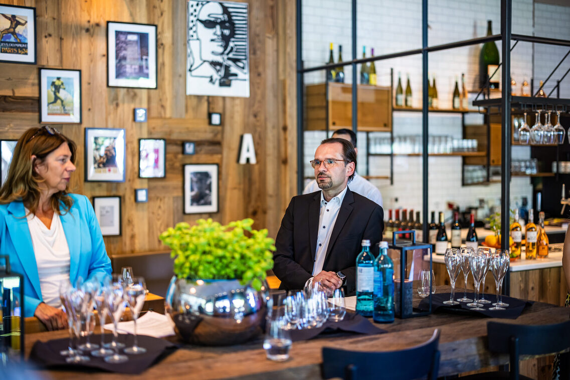 Ein Mann und eine Frau stehen am Stehtisch und unterhalten sich