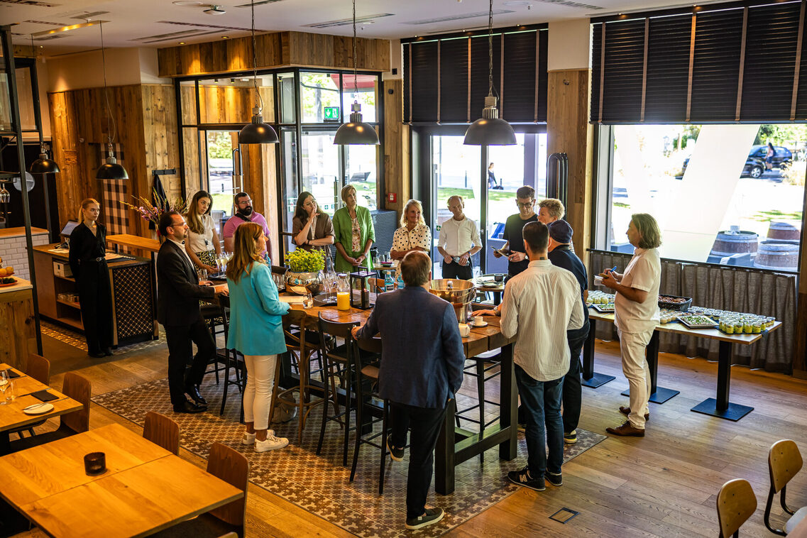 Menschen stehen am Stehtisch im Restaurant und unterhalten sich