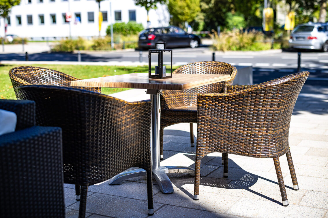 Ein Holztisch und drei Stühle draußen auf der Terasse