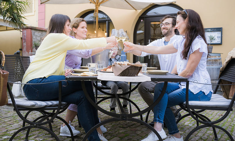 Rheingauer Schlemmerwochen: Drei Frauen und ein Mann sitzen am Tisch und prosten sich mit Wein zu.