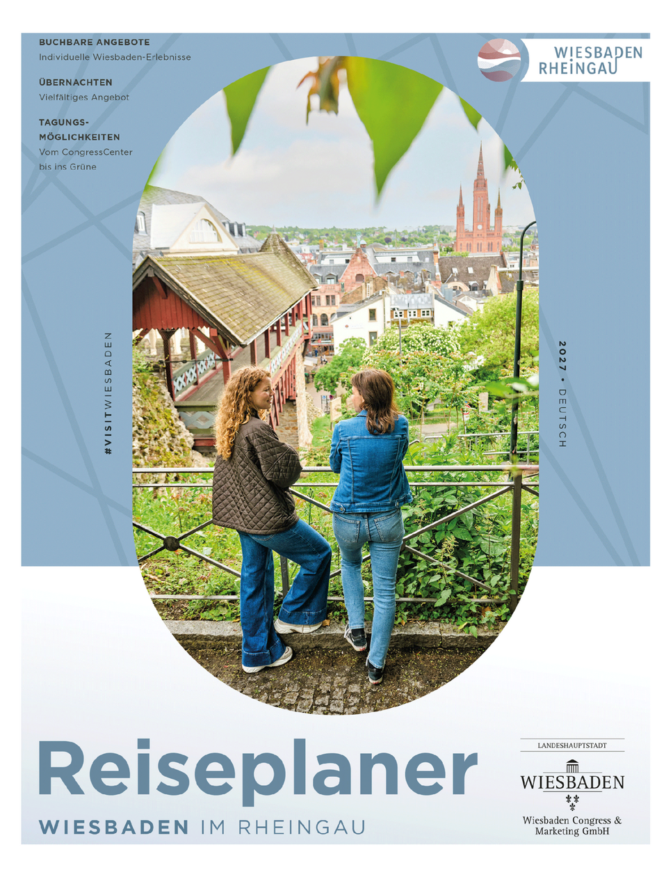 Zwei Frauen stehen auf einer grünen Aussichtsplattform und schauen auf eine Stadt