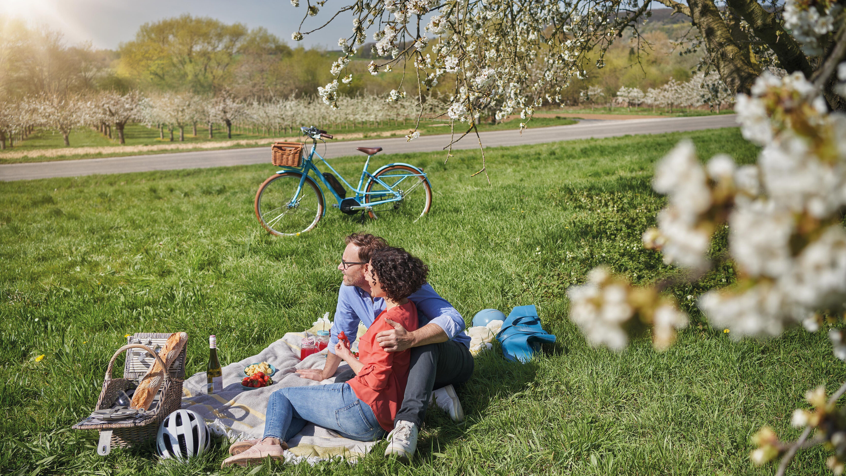 Frauensteinerkirschblüte Picknick auf der Wiese - Pärchen sitzt im Gras.